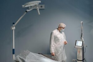A healthcare professional in protective attire operating advanced medical equipment in a clinic.