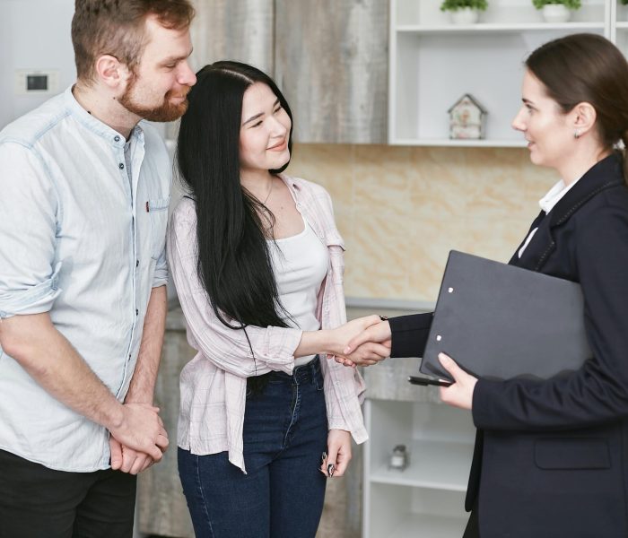 pexels-photo-7734597-7734597 A young couple shakes hands with a real estate agent during a home tour or negotiation in a modern setting.